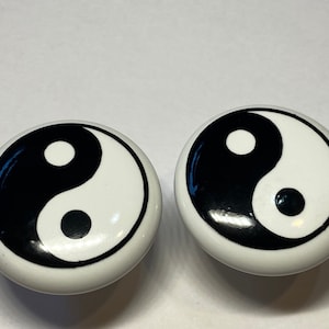 May include: Two white ceramic knobs with black yin yang symbols.