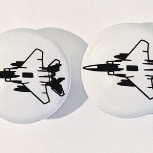 May include: Two white ceramic knobs with a black silhouette of a fighter jet on each.