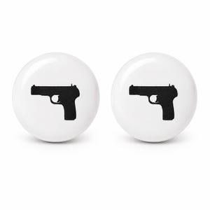 May include: Two round white ceramic cabinet knobs, each featuring a solid black silhouette of a semi-automatic handgun printed in the center. The knobs have a smooth, glossy finish and a circular shape, providing a clean and simple appearance.