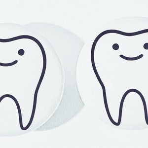 May include: Two white round stickers with black outlines of cartoon teeth with smiling faces.