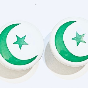 May include: Two white round buttons with a green crescent moon and star design.