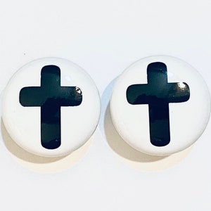 May include: Two white round buttons with a black cross design.
