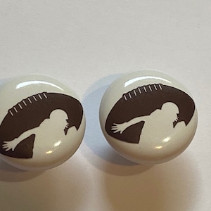 May include: Two white ceramic cabinet knobs with a brown silhouette of a football player running with the ball.