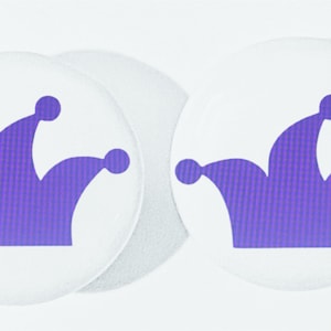 May include: Two white round stickers with a purple jester's hat design.