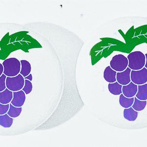 May include: Two white round stickers with a purple grape design. The grapes are outlined in white and have a green stem and leaves.