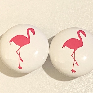 May include: Two white ceramic knobs with pink flamingo silhouettes.