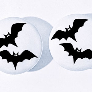 May include: Two white round stickers with black bat silhouettes. Each sticker features three bats in a flying position.