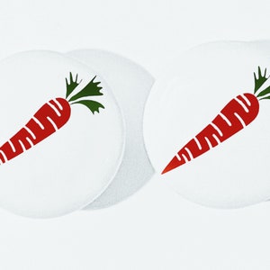 May include: Two white round stickers with a red carrot with green leaves on each.