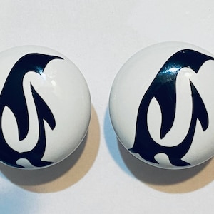 May include: Two white ceramic knobs with black penguin silhouettes. The penguins are facing to the right and have a simple, stylized design.