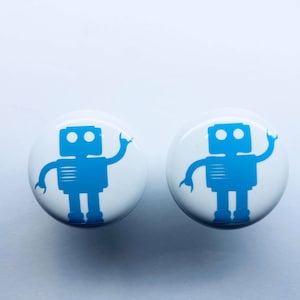 May include: Two white round buttons with a blue robot silhouette on each. The robot is waving with one arm and has two eyes.
