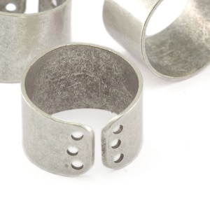 May include: Three silver rings with a textured finish and a cutout design. The rings are open on one side and have a slightly rounded shape.