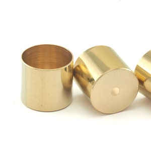 May include: Three gold metal candle holders, each with a cylindrical shape and a smooth, polished finish.