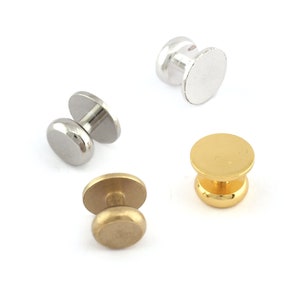 May include: Three metal button snaps in silver and gold. The snaps are round and have a raised centre.