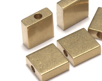 May include: Five gold-colored square metal beads with a hole in the center. The beads are arranged in a cluster on a white background.