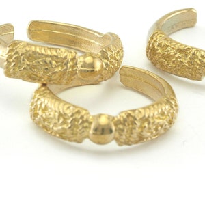 May include: Three gold-toned rings with a textured surface and a small bead on each ring.