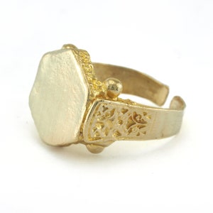 May include: A gold ring with a hexagonal shaped top and intricate filigree detailing on the band.