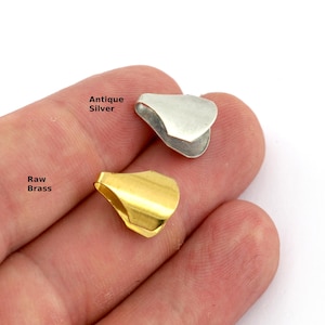 Puede incluir: Se muestran dos componentes de joyería metálicos, uno plateado antiguo y otro de latón en bruto. Los componentes son pequeños, con forma curva de pétalo. El texto "Antique Silver" y "Raw Brass" es visible.