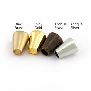 Könnte beinhalten: Vier Metall-Kordelenden in verschiedenen Ausführungen: Rohmessing, glänzendes Gold, Antikmessing und Antik Silber.