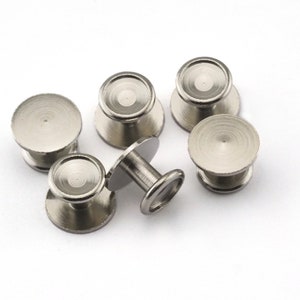 May include: Five silver metal buttons with a raised center and a smooth, slightly textured surface. The buttons are arranged in a semi-circle on a white background.