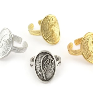 May include: Three silver rings with a flower design. The rings are oval shaped and have a textured surface. The flower design is raised and detailed.