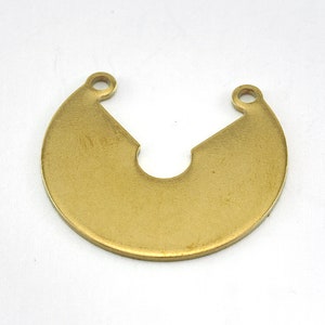 Könnte beinhalten: Ein messingfarbener, halbmondförmiger Anhänger mit einem ausgeschnittenen Bereich in der Mitte und einem kleinen Loch an jedem Ende. Der Anhänger hat eine glatte Oberfläche und eine leicht gebogene Form, geeignet für die Schmuckherstellung.