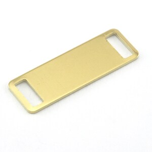 May include: A gold-colored metal tag with two rectangular cutouts. The tag is flat and rectangular.