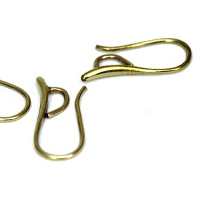May include: Two gold-toned earring hooks, one is bent into a U-shape, the other is a straight hook.