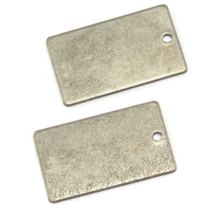 May include: Two rectangular metal tags with a distressed, textured finish. Each tag has a small, circular hole near one corner. The tags are a muted silver color and appear to be made of a durable material.