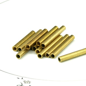 May include: A group of brass tubes, some stacked on top of each other, with a single tube lying horizontally in the foreground.