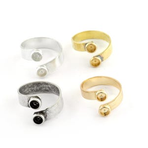 May include: Four adjustable rings with two open bezels for adding stones or charms. The rings are available in silver, antique silver, gold, and brass.
