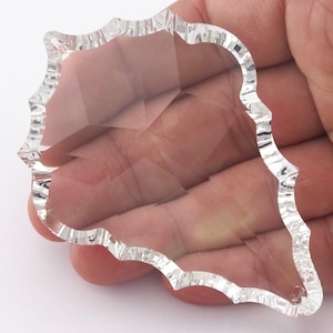 以下が含まれることがあります： 波打つ縁のある透明なクリスタルプリズム。プリズムは涙の形をしており、ファセットデザインが施されています。