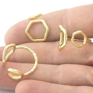 Puede incluir: Tres anillos de color dorado, uno con forma hexagonal, otro con forma curva y otro con forma redonda simple.
