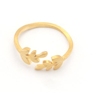 Könnte beinhalten: Ein goldener Ring mit einem zarten Blattdesign. Der Ring ist offen und verstellbar, um verschiedenen Fingergrößen zu passen.
