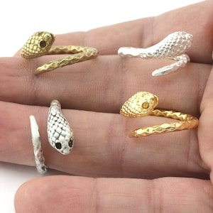 May include: Four silver and gold snake rings. The rings are coiled and feature a snake head with a textured surface.