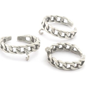 May include: Three silver chain rings with a dangling charm on two of the rings.