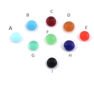 May include: A collection of nine round beads in various colors, including light blue, turquoise, red, orange, coral, green, dark blue, and black. Each bead is smooth and evenly colored, with a glossy finish. The beads are arranged on a white background.