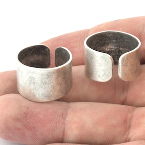 Könnte beinhalten: Zwei silberne offene Ringe mit einer strukturierten Oberfläche. Die Ringe sind dick und haben ein breites Band.
