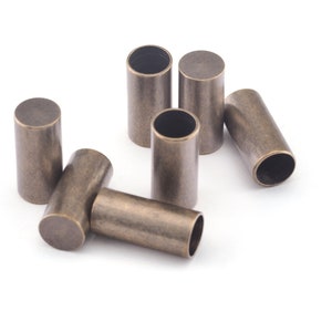 May include: Six antique gold metal end caps for cords or ropes. The end caps are cylindrical and have a smooth, slightly textured surface.