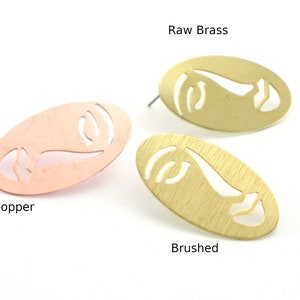 May include: Three oval-shaped earrings in copper, raw brass, and brushed metal. Each earring features a cutout design of a face profile. The text "Raw Brass", "Copper", and "Brushed" are visible.