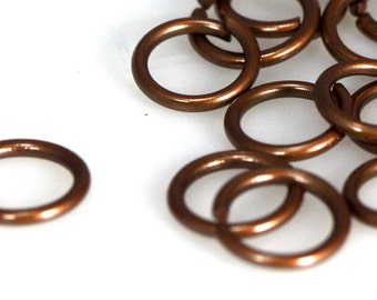 Könnte beinhalten: Ein Haufen kleiner, kupferfarbener Sprungringe. Die Ringe haben einen Durchmesser von etwa 1,2 cm und sind perfekt für die Schmuckherstellung.