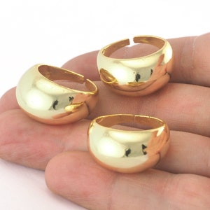 May include: Three gold-colored rings with a rounded, smooth, and slightly domed design. The rings are stacked on top of each other.