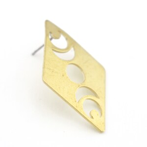 May include: A gold-toned earring with a diamond-shaped design featuring a cutout of three crescent moons.