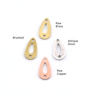 May include: Four teardrop-shaped metal charms with two holes each. The charms are in raw brass, brushed brass, antique silver, and raw copper.