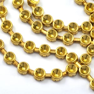 May include: A gold chain of round, dome-shaped metal beads. The beads are connected by small metal bars.
