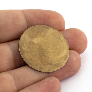 以下が含まれることがあります： わずかにテクスチャ加工された表面を持つ、丸い金色の金属製の円盤