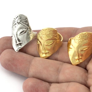 Peut inclure: Trois bagues en argent et en or avec un motif de visage. Les bagues sont sur une main.