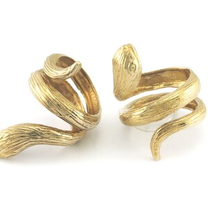 Puede incluir: Dos anillos de serpiente de color dorado. Los anillos están enrollados y tienen una superficie texturizada.