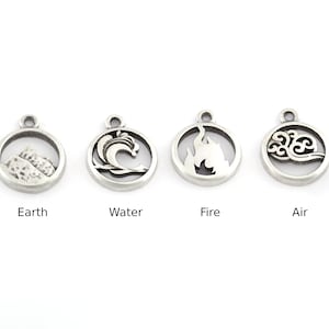 May include: Four silver charms with different symbols representing the four elements: earth, water, fire, and air. The charms are round and have a cutout design.