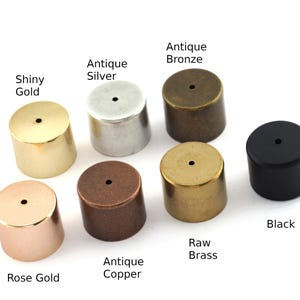 May include: Assortment of eight metal end caps in different finishes: shiny gold, antique silver, antique bronze, raw brass, antique copper, rose gold, and black. Each cap has a small hole in the centre.