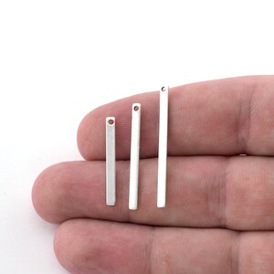 May include: Three silver metal bar pendants of varying lengths with a hole at the top for attaching to jewelry.